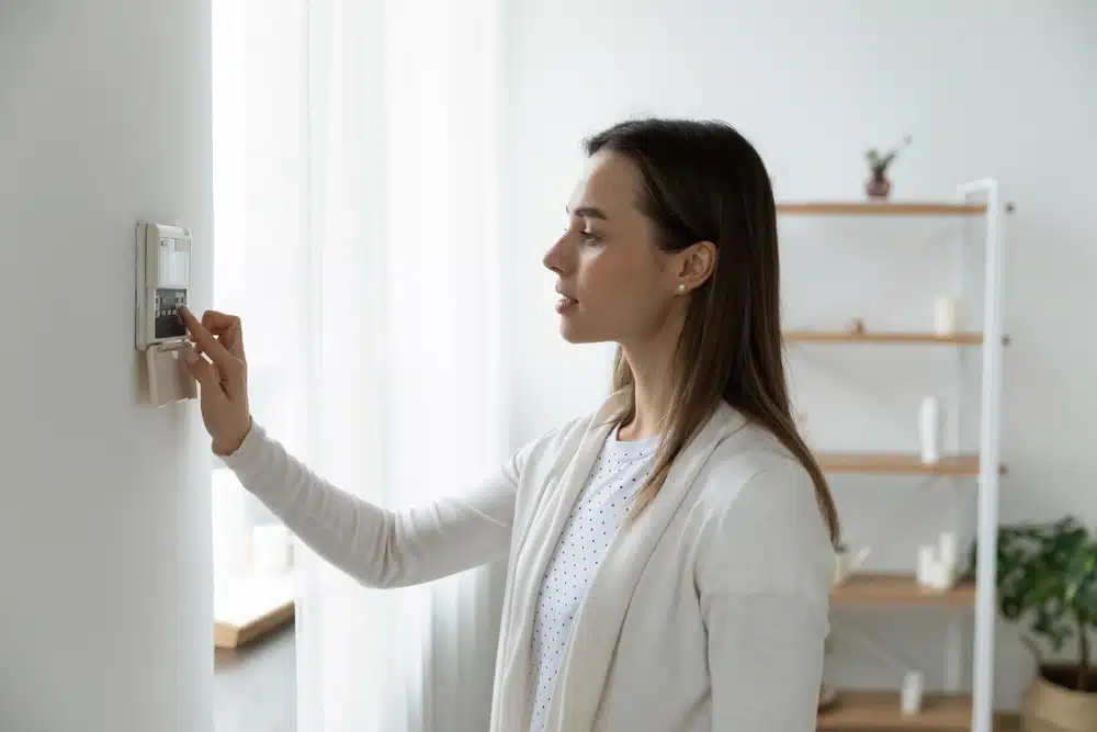 woman adjusting home thermostat