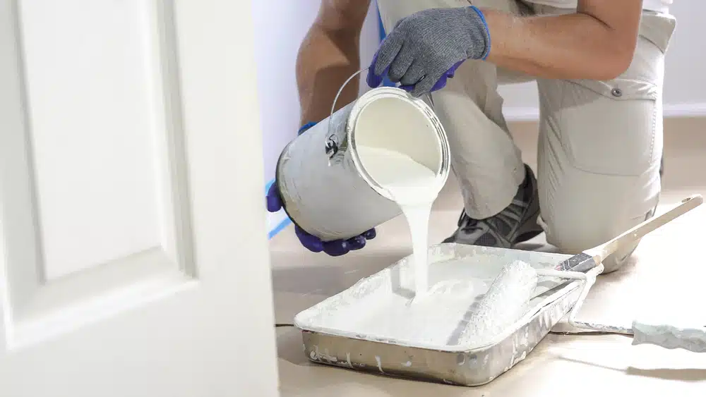 man pouring paint into tray